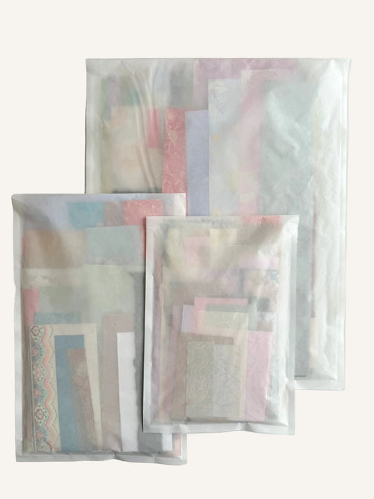 An assortment of textured white and patterned Xuan paper scraps in various sizes for scrapbooking and collage.